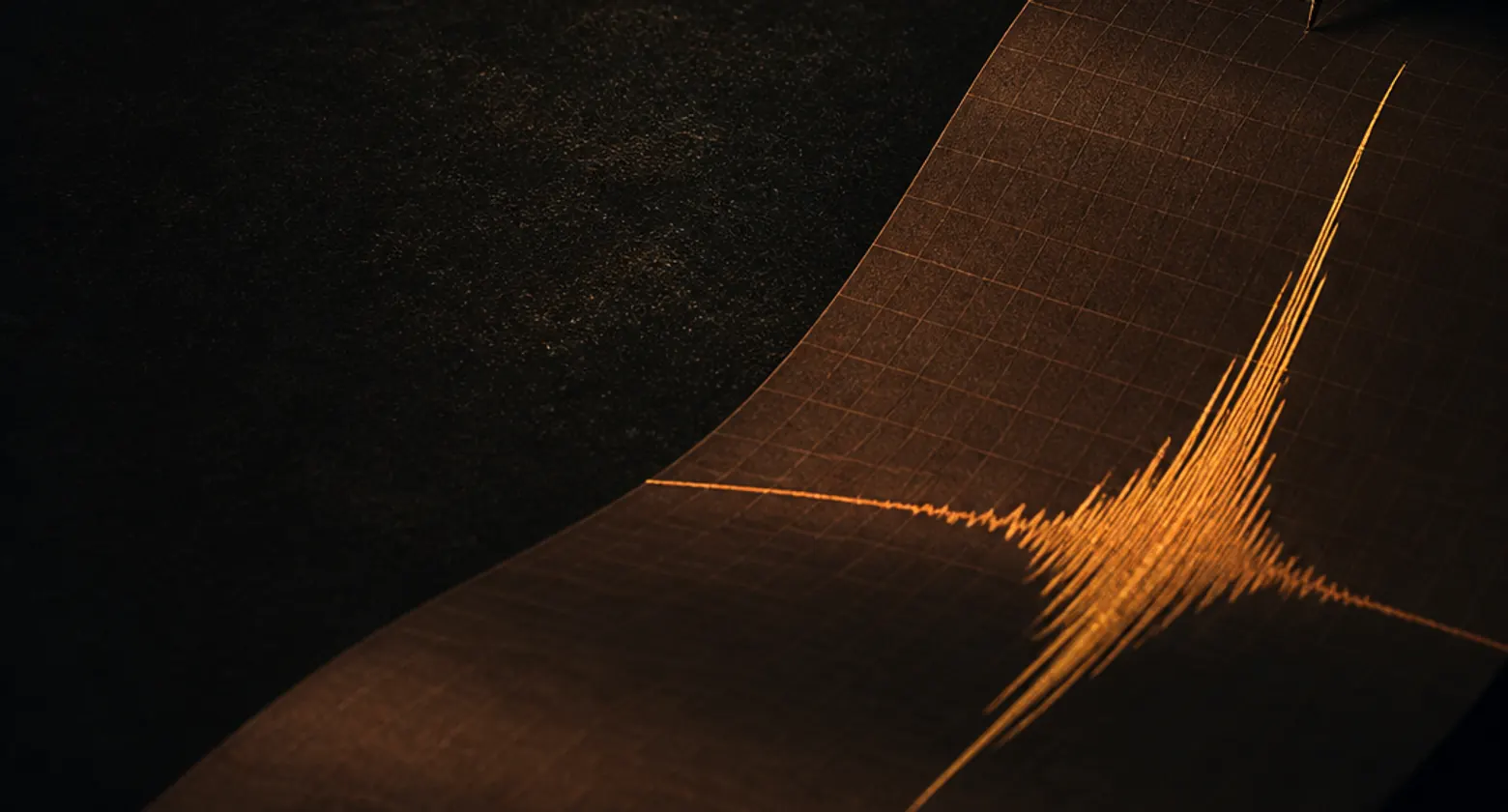 A wall of dark ticker tape with a single towering orange spike on the right